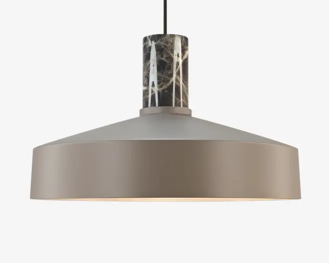 En moderne pendellampe med en bred, mat taupefarvet metalskærm med glat overflade. Øverst på lampen er der en cylindrisk detalje i mørk marmor med hvide årer, som giver et elegant og kontrastfuldt udtryk. Lampen hænger i en sort ledning, og det samlede design er minimalistisk og nutidigt.