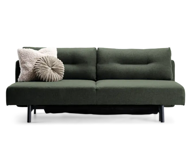 En moderne sofa med mørkegrønt betræk og minimalistisk design, med rene linjer og sorte metalben. Sæde- og ryghynderne har diskrete knapdetaljer, der giver ekstra struktur. To pyntepuder ligger i venstre side: en firkantet, cremefarvet og fluffy pude samt en rund, plisseret pude i en lys taupe farve.