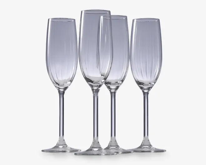 Sæt med fire klare glasfløjter med høje, slanke skåle og lange stilke. Hver glas har diskrete lodrette riller langs skålen, hvilket giver et elegant og tekstureret udtryk. Fodene er brede og flade for stabilitet.
