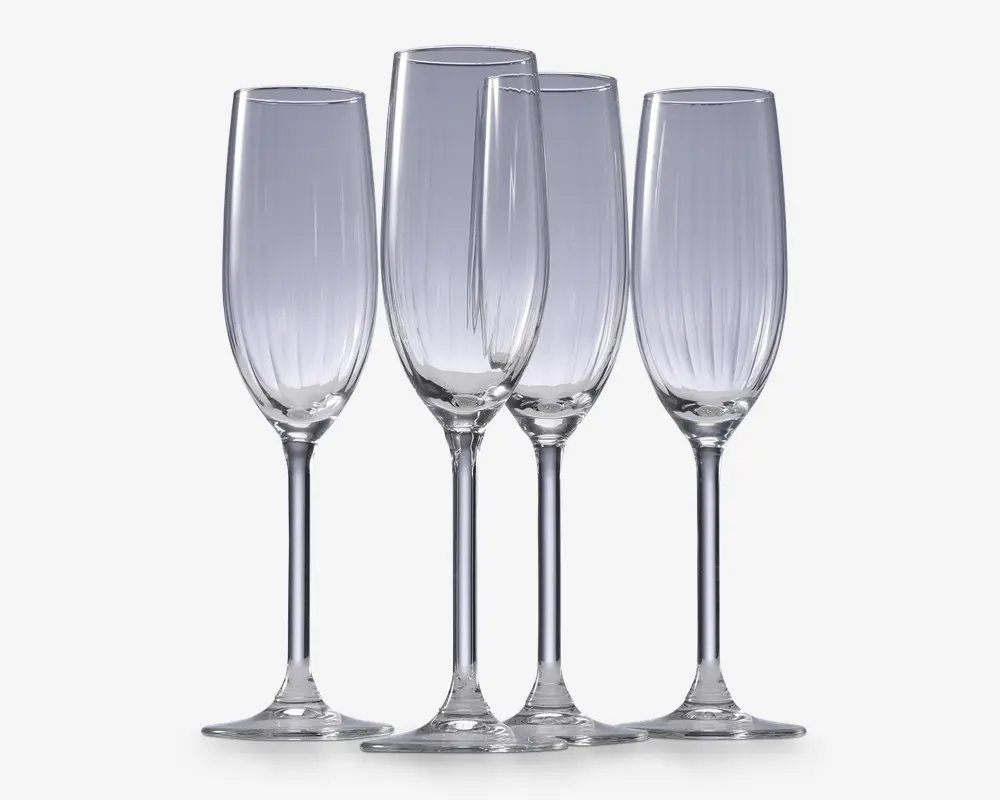 Sæt med fire klare glasfløjter med høje, slanke skåle og lange stilke. Hver glas har diskrete lodrette riller langs skålen, hvilket giver et elegant og tekstureret udtryk. Fodene er brede og flade for stabilitet.