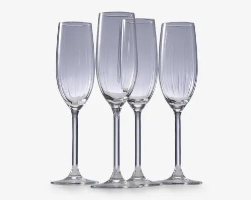 Sæt med fire klare glasfløjter med høje, slanke skåle og lange stilke. Hver glas har diskrete lodrette riller langs skålen, hvilket giver et elegant og tekstureret udtryk. Fodene er brede og flade for stabilitet.