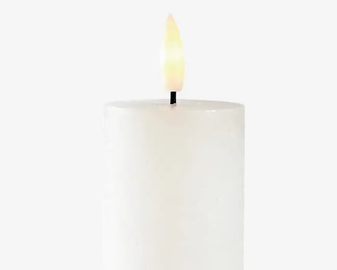 En cylindrisk, hvid søjle med en glat overflade og flad top. Toppen har en sort væge med en realistisk udseende, let buet flamme, der udsender et blødt gult skær. Udseendet er enkelt og minimalistisk, velegnet til forskellige dekorative formål.