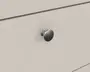 Nærbillede af en skuffe med en rund knop i børstet metal, der har en glat, let buet overflade. Knoppen er monteret på en flad, lysebeige skuffefront og har et enkelt, klassisk design med en lille dekorativ ring ved basen.