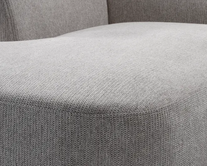 Nærbillede af en sædehynde betrukket med lysegråt vævet stof med en diskret tekstureret overflade. Hynden fremstår tyk og fast med afrundede kanter og en glat, ensartet finish. Stoffet har en tæt vævning, hvilket giver et holdbart og moderne udtryk.