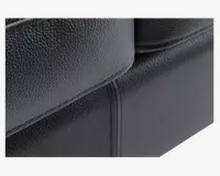 Nærbillede af en sort overflade i kunstlæder med en fin, nubret tekstur. Syningerne er tydelige og lige, hvilket vidner om god håndværksmæssig kvalitet. Materialet ser glat og let blankt ud, hvilket tyder på holdbarhed og nem rengøring.