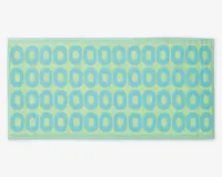 Rektangulært produkt med en blød, tekstureret overflade, der har et gentagende mønster af blå ovale ringe på en lysegrøn baggrund. Kanterne er pænt syet, og det samlede design er moderne og legende.
