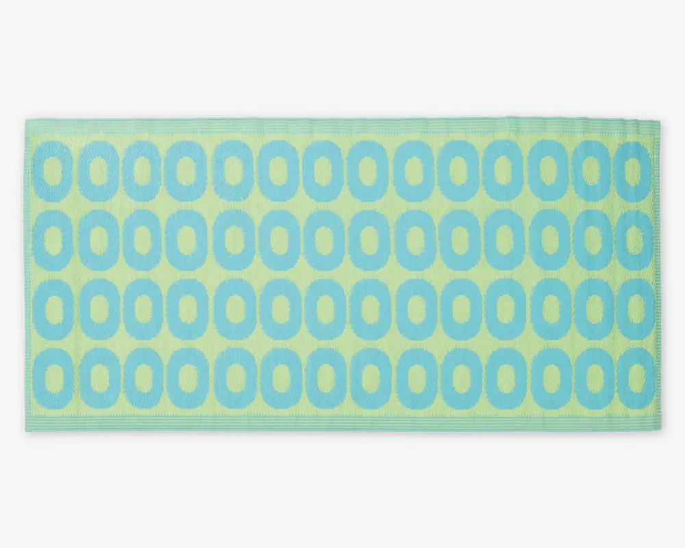 Rektangulært produkt med en blød, tekstureret overflade, der har et gentagende mønster af blå ovale ringe på en lysegrøn baggrund. Kanterne er pænt syet, og det samlede design er moderne og legende.