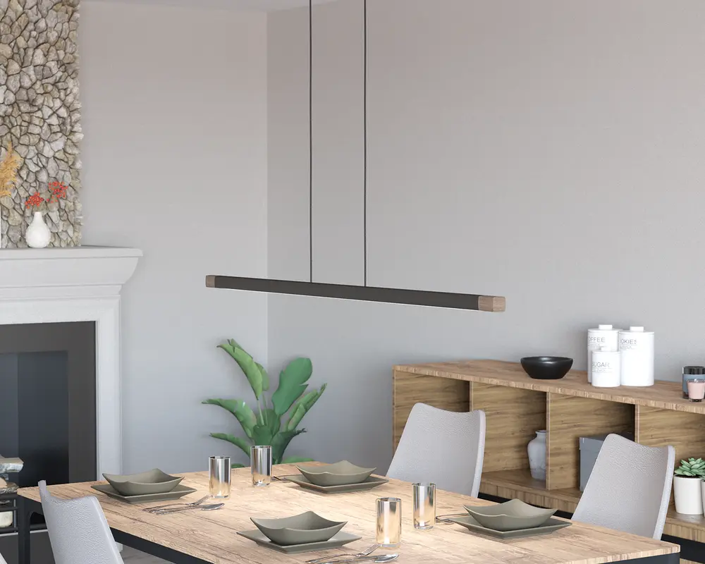 Et moderne, minimalistisk pendellampe med en lang, slank rektangulær form, ophængt fra loftet med to tynde sorte ledninger. Lampen har en mat sort finish med naturlige trædetaljer i enderne, hvilket giver et stilrent og nutidigt udtryk. Den er designet til at give jævn belysning over spisebordet nedenunder.
