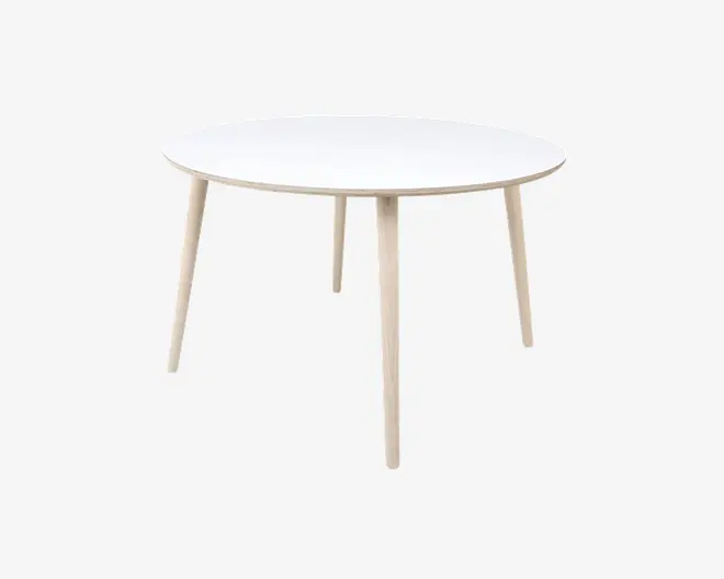 Et rundt bord med en glat, hvid bordplade og fire lyse træben, der er let skråtstillede udad. Designet er minimalistisk og moderne med rene linjer og en slank profil. Bordet virker solidt og egner sig til små spiseområder eller som et alsidigt møbel.