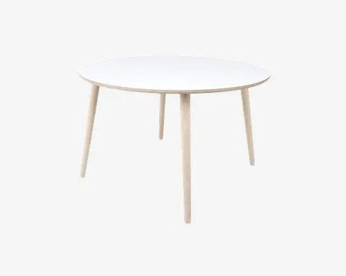 Et rundt bord med en glat, hvid bordplade og fire lyse træben, der er let skråtstillede udad. Designet er minimalistisk og moderne med rene linjer og en slank profil. Bordet virker solidt og egner sig til små spiseområder eller som et alsidigt møbel.