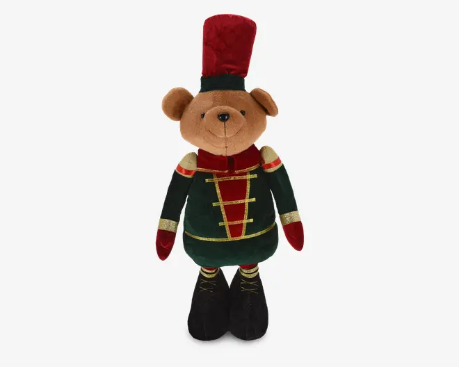 Bamse i plys klædt i en festlig soldateruniform med mørkegrøn jakke, guldfarvede detaljer og røde accenter, samt dekorative guldknapper og matchende manchetter. Bamsen har en høj, rød fløjlshat med grøn kant og sorte støvler med gulddetaljer. Ansigtet er blødt og venligt med broderet næse og smil.