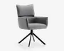 En moderne stol med gråt polstret sæde, ryglæn og armlæn. Stolen har en blød, polstret ryg for ekstra komfort og et kantet, firkantet design. Den står på en sort metalfod med fire skråtstillede ben og kan dreje, hvilket giver et moderne udtryk, der passer til både kontor og hjem.