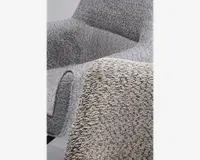 Nærbillede af en stol betrukket med et tekstureret, boucle-lignende stof i en lys grå farve. Stoffet har en blød, nopret overflade, der giver et hyggeligt og indbydende udtryk. Stolen har glatte, afrundede kanter og et moderne, minimalistisk design.