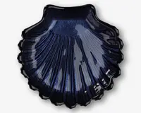 En blank, mørkeblå skål formet som en kammuslingeskal med detaljerede riller og en tekstureret overflade. Kanterne er bølgede, og den skinnende finish giver et elegant og dekorativt udtryk.