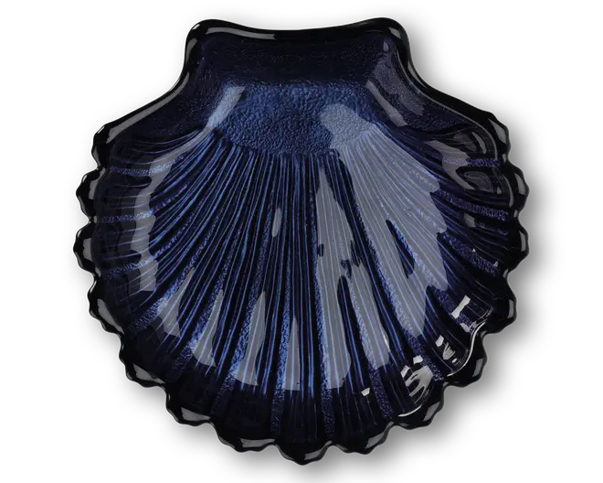 En blank, mørkeblå skål formet som en kammuslingeskal med detaljerede riller og en tekstureret overflade. Kanterne er bølgede, og den skinnende finish giver et elegant og dekorativt udtryk.