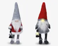 To plyssede nissefigurer med lange hvide skæg og runde næser. Nissen til venstre har en høj grå hue, en rød sweater med hvid kant og holder en lille sort lanterne. Nissen til højre har en høj rød hue, gråt tøj og holder også en lanterne, der udsender et blødt gult lys. Begge har bløde, lodne teksturer og hængende ben.