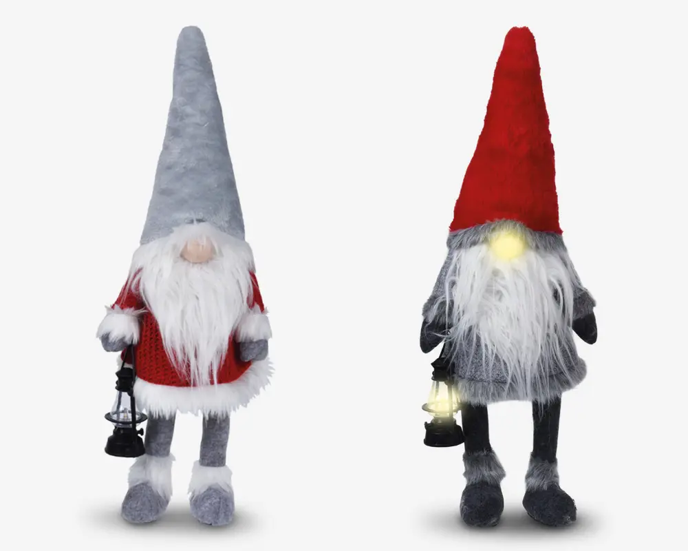 To plyssede nissefigurer med lange hvide skæg og runde næser. Nissen til venstre har en høj grå hue, en rød sweater med hvid kant og holder en lille sort lanterne. Nissen til højre har en høj rød hue, gråt tøj og holder også en lanterne, der udsender et blødt gult lys. Begge har bløde, lodne teksturer og hængende ben.