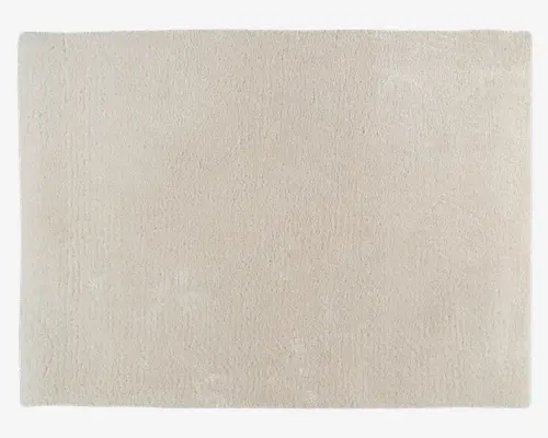 Et rektangulært, lysebeige tæppe med en blød, plysset tekstur. Overfladen fremstår ensartet og glat uden synlige mønstre eller designs, hvilket giver et minimalistisk og moderne udtryk. Kanterne er pænt afsluttede, hvilket bidrager til et rent og enkelt look.