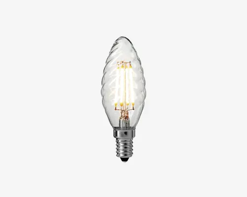 Klar glaspære med dekorativt snoet design, synlige LED-filamenter indeni og en blank, metallisk skruefatning. Pæren har form som en flamme eller et blad, hvilket giver et elegant og vintage udseende.