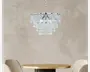 En rund lysekrone med flere lag af klare, dråbeformede krystalprismer, der hænger fra en poleret kromramme. Krystallerne er arrangeret i koncentriske cirkler, hvilket skaber en kaskadeeffekt, der reflekterer lyset smukt. Lysekronen er ophængt i en matchende kromkæde, hvilket giver et elegant og moderne udtryk.