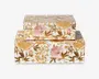 Sæt med to rektangulære opbevaringskasser, hver med en blank overflade og et detaljeret blomstermønster i guld, lyserød og grønne nuancer. Kasserne har et sømløst design, hvor blomstermotivet fortsætter rundt om alle sider, og blomsterne har fine blade og blomsterhoveder. Den større kasse fungerer som base, mens den mindre kasse er stablet ovenpå. Begge kasser har hængslet låg og er designet til dekorativ opbevaring.