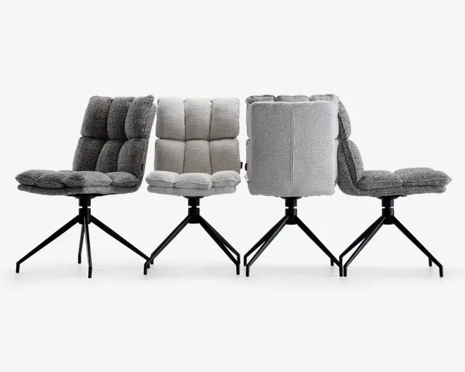 Fire moderne stole med blød, polstret og kvadratsyet betræk i forskellige grå nuancer, med tykke, komfortable sæder og rygstøtter. Hver stol har en robust sort metalbase med fire skråtstillede ben, hvilket giver stabilitet og et moderne udtryk. Stofstrukturen er synligt blød og vævet, og stolene vises fra flere vinkler for at fremhæve designet.