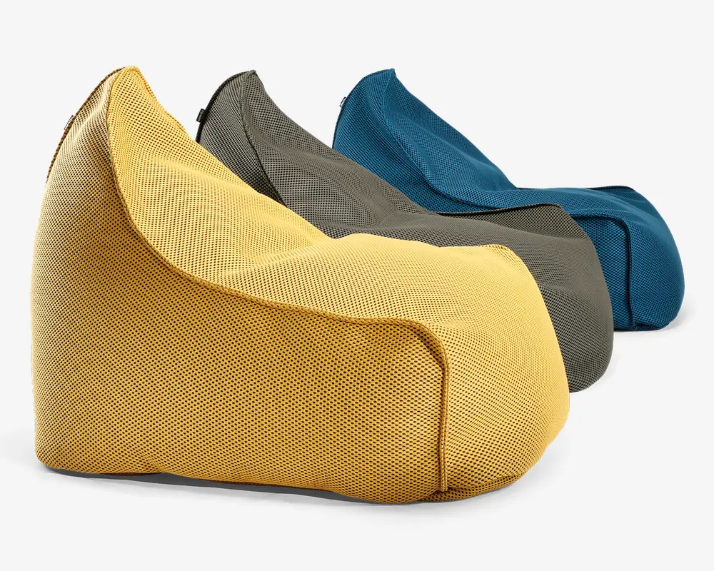 Tre sækkestole vises i farverne gul, grå og blå. Hver stol har en blød, afrundet form med en støttende ryg og et bredt, lavt sæde. Stoffet ser ud til at være et åndbart mesh-materiale, og syningerne er forstærkede for holdbarhed. Stolene er designet til at give komfortabel, afslappet siddeplads og egner sig til forskellige indendørs miljøer.