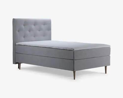 Enkeltseng med et moderne, minimalistisk design og lysegråt betræk. Hovedgærdet er højt og rektangulært med en knap-tuftet mønster, der giver ekstra struktur. Sengen står på fire koniske træben, hvilket giver et let hævet udtryk. Madrassen virker mellemtyk, og den samlede konstruktion fremstår solid og komfortabel.