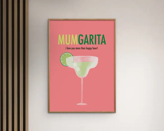 Indrammet plakat med lyserød baggrund, der viser en sjov illustration af et margaritaglas med en limeskive på kanten. Øverst står teksten 'MUMGARITA' med store gule og grønne bogstaver, og nedenunder står der med mindre sort tekst: 'i love you more than happy hour!' Designet er moderne og muntert, velegnet som gave.