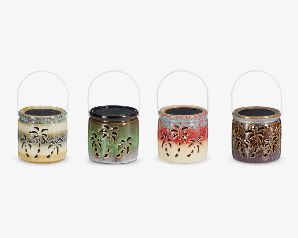 Sæt med fire dekorative lanterner, hver med metalhåndtag og keramisk krop med udskårne palmetræsmotiver. Lanternerne har forskellige farvekombinationer: én er creme og blå, én er grøn og brun, én er creme og rød, og den sidste er brun og lilla. Udskæringerne i mønsteret lader lyset skinne igennem og skaber en tropisk stemning.