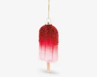Et dekorativt ornament formet som en ispind, med en farvegradient fra lyserød til rød. Den øverste del er dækket af røde, teksturerede perler, der ligner krymmel eller slik, og ornamentet hænger i en gylden løkke og snor. Ispindens træpind er synlig i bunden, hvilket giver et realistisk udseende.