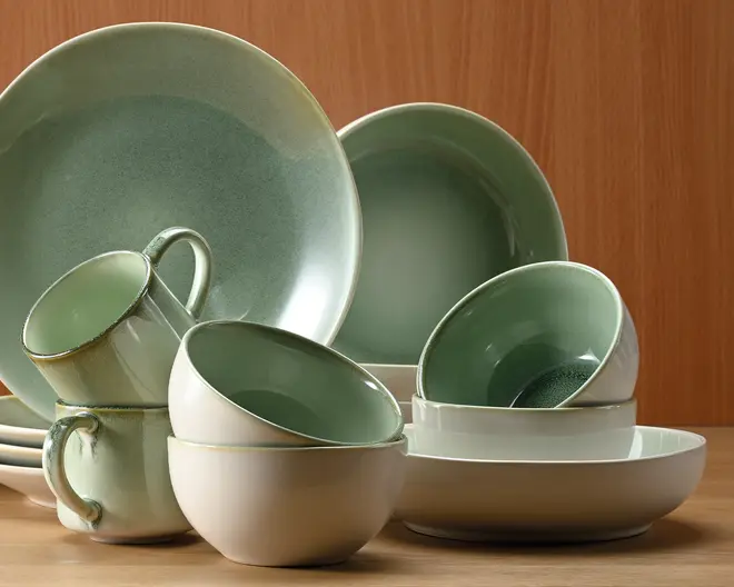 Et sæt keramikservice med en blød grøn farvegradient på indersiden og en glat, offwhite yderside. Sættet indeholder store middagstallerkener, skåle og krus, alle med en diskret blank finish. Kanterne på krusene og skålene har en lidt mørkere grøn kant, som giver et elegant modspil. Delene har et moderne, minimalistisk design med bløde, afrundede former, velegnet til både hverdags- og festbrug.