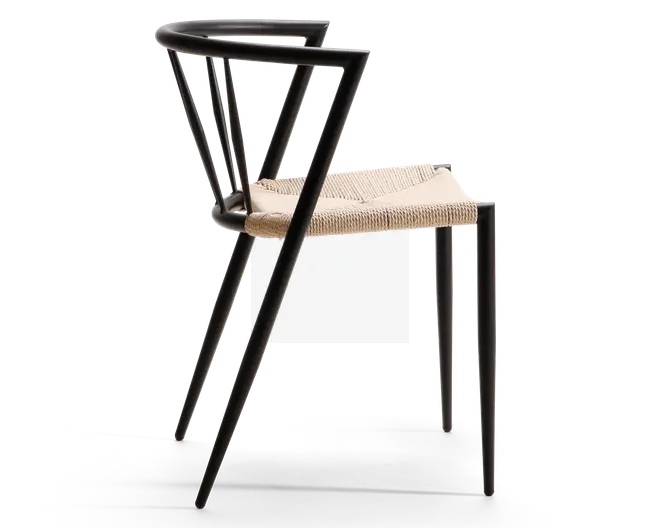 Sidebillede af en moderne stol med sort metalstel og markante, geometriske linjer. Ryglæn og armlæn er integreret i stellet og danner en sammenhængende, minimalistisk struktur. Sædet er lavet af flettet naturfiber, hvilket giver en tekstureret og komfortabel siddeflade. Designet er stilrent og nutidigt med fokus på rene linjer og kontrasterende materialer.