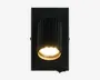 Rektangulær vægmonteret lampe med mat sort finish og en lodret rillet, cylindrisk lampeholder. Lyskilden er forsænket og udsender et varmt, fokuseret lys nedad. Lampens inderkant har en guldfarvet tone, som giver et elegant og kontrastfyldt udtryk. Egnet til moderne indretning, hvor lampen kombinerer dekorativt og funktionelt lys.
