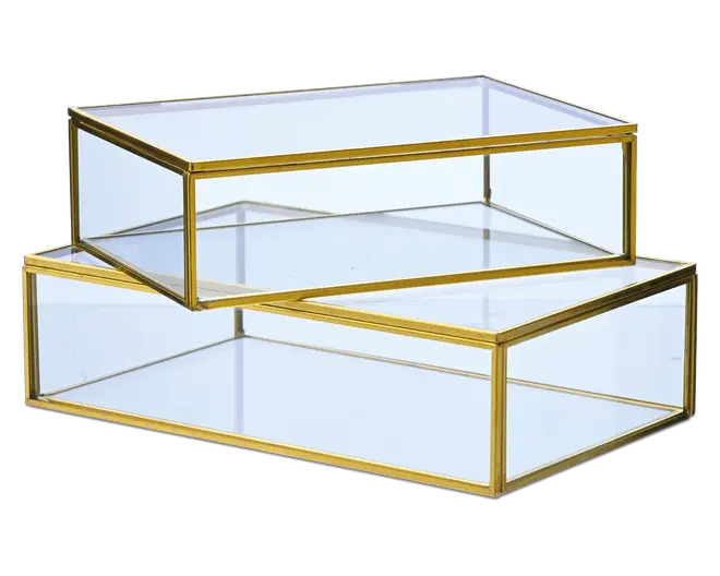 Sæt med to rektangulære glasæsker med guldfarvede metalrammer. Hver æske har klare glaspaneler på alle sider, inklusive låget, hvilket giver fuldt overblik over indholdet. Guldkanten tilføjer et elegant og moderne udtryk. Æskerne kan stables, hvor den mindre passer ovenpå den større. Velegnet til opbevaring eller udstilling af smykker, minder eller dekorative genstande.