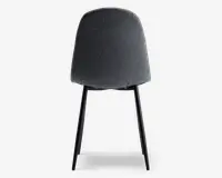 Stol med buet, polstret ryglæn i mørkegråt stof. Bagsiden er glat og rundet uden synlige syninger eller knapper. Stolen har slanke, sorte metalben, der er let udadgående for stabilitet.