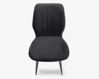 Stol med høj, let buet ryg med lodrette syninger for ekstra struktur. Sædet er bredt og afrundet, polstret med mørkt stof. Benene er slanke og skråtstillede, lavet af metal med mat finish, hvilket giver stolen et moderne og minimalistisk udtryk.