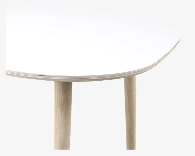 Nærbillede af et bordhjørne med en glat, hvid bordplade med afrundede kanter og en tynd profil. Bordet har solide, cylindriske ben af lyst træ, hvilket giver et moderne og minimalistisk udtryk.