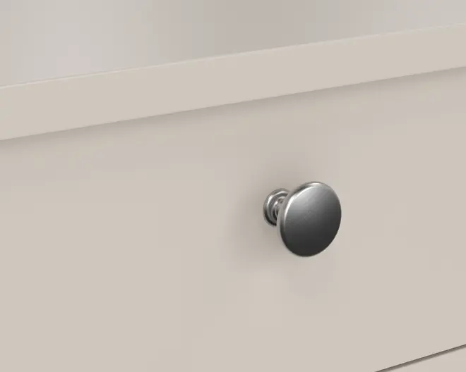 Nærbillede af en skuffe med en rund knop i børstet metal med en glat, mat overflade. Knoppen er monteret på en lys, ensfarvet skuffefront og har et enkelt, moderne design med en let hævet sokkel for nemt greb.