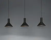 Tre pendellamper med mat sort finish, hver med en bred, konisk skærm og en slank cylindrisk hals. Lamperne hænger fra tynde sorte ledninger og har et minimalistisk og moderne udtryk. Indersiden af skærmene ser ud til at være lysere, hvilket forbedrer lysrefleksionen.