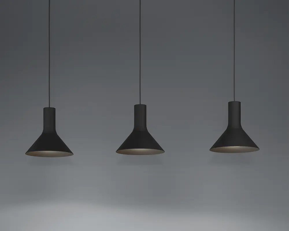 Tre pendellamper med mat sort finish, hver med en bred, konisk skærm og en slank cylindrisk hals. Lamperne hænger fra tynde sorte ledninger og har et minimalistisk og moderne udtryk. Indersiden af skærmene ser ud til at være lysere, hvilket forbedrer lysrefleksionen.