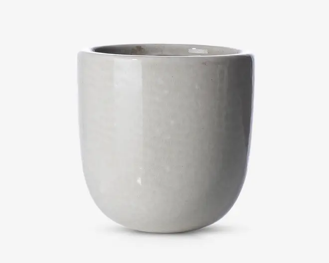 En glat, rund keramisk beholder med en blank lysegrå overflade. Overfladen er jævn og uden dekoration, hvilket giver et minimalistisk og moderne udtryk. Kanten er let tyk, og formen er cylindrisk med en blødt buet bund.