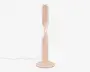 En moderne bordlampe med et slankt, lodret design og en blød mat ferskenfarvet finish. Lampen har en unik snoet lysstribe, der snor sig rundt om den centrale søjle og giver et moderne og kunstnerisk udtryk. Den står på en rund, flad fod for stabilitet og har en synlig ledning, der går ud fra bunden.