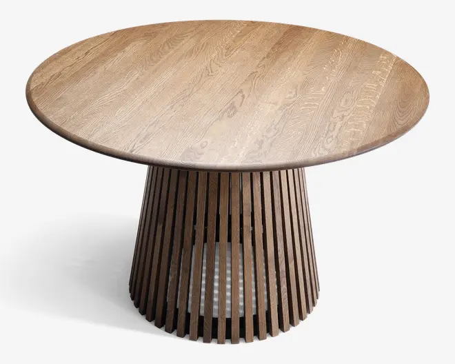 Rundt bord i træ med en glat bordplade, der viser naturlig træstruktur. Bordet har en markant piedestal-fod bestående af lodrette trælameller med mellemrum imellem, hvilket giver et let og moderne udtryk. Foden udvider sig let mod gulvet for et stilfuldt design.
