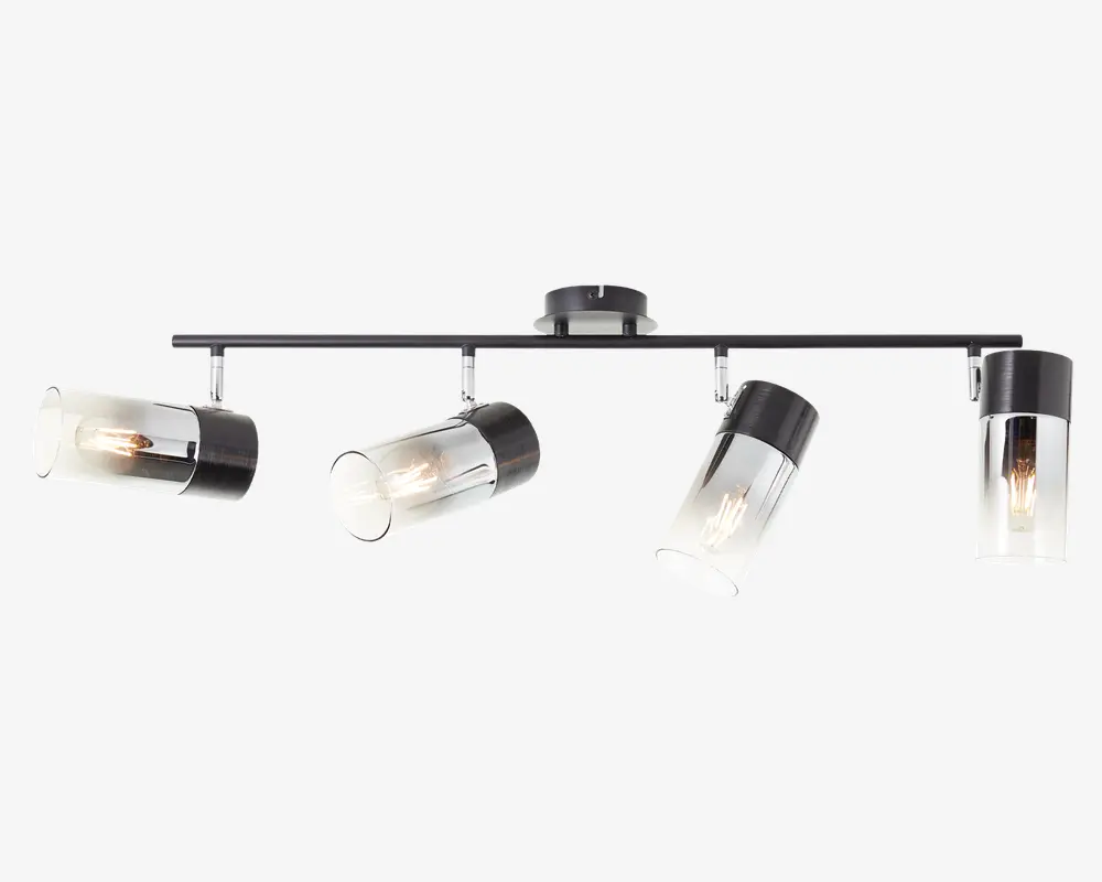 Moderne loftlampe med fire justerbare cylindriske spotlys, der har klare glasafskærmninger og sorte metaldetaljer. Spotlysene er monteret på en lige, vandret stang, som er fastgjort til en rund loftbase, hvilket giver mulighed for retningsbestemt belysning. Pærerne er synlige inde i glasskærmene, hvilket giver et moderne udtryk.
