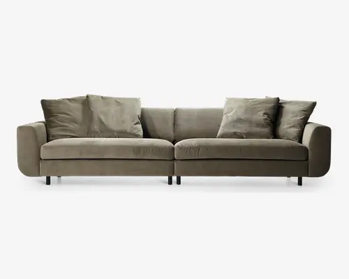 Moderne sofa med minimalistisk design, polstret i et blødt, lysebrunt stof. Sofaen har brede, bløde sæde- og ryghynder for ekstra komfort, med tre store rygpuder og to armlæn. Sofaen står på korte, solide sorte ben, hvilket giver et lavt og stilrent udtryk. Det samlede udseende er enkelt og moderne, velegnet til forskellige stuer.