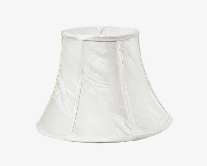 En klokkeformet lampeskærm lavet af hvidt stof med en let krøllet struktur. Skærmen har lodrette stofpaneler adskilt af tynde, syede sømme og en let udvidet bundkant. Top- og bundkanterne er afsluttet med en glat, forstærket kant for ekstra holdbarhed og et pænt udseende.
