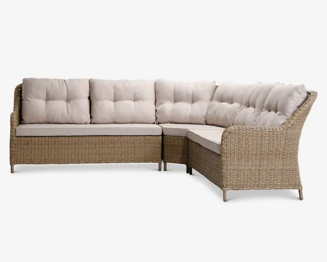L-formet hjørnesofa med en lys brun flettramme og beige, polstrede puder med knapper. Sofaen har høje armlæn og en støttende ryg, med tykke, bløde sæde- og ryghynder for ekstra komfort. Designet er moderne og egnet til både indendørs og udendørs brug, og giver god siddeplads til flere personer.