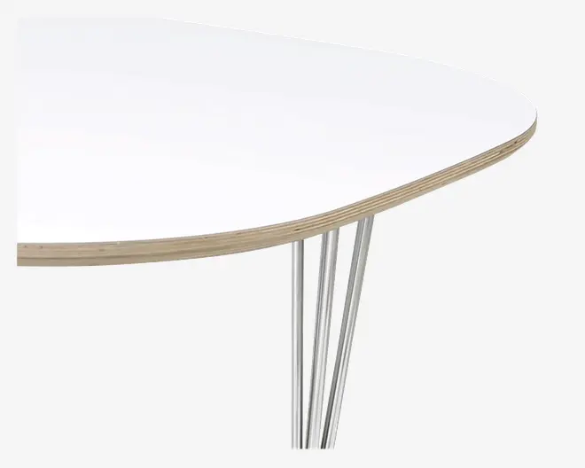 Nærbillede af et bordhjørne med en glat, afrundet hvid bordplade og synlig lagdelt trækant. Bordet understøttes af slanke, skrå metalben med kromfinish, hvilket giver et moderne og minimalistisk udtryk.