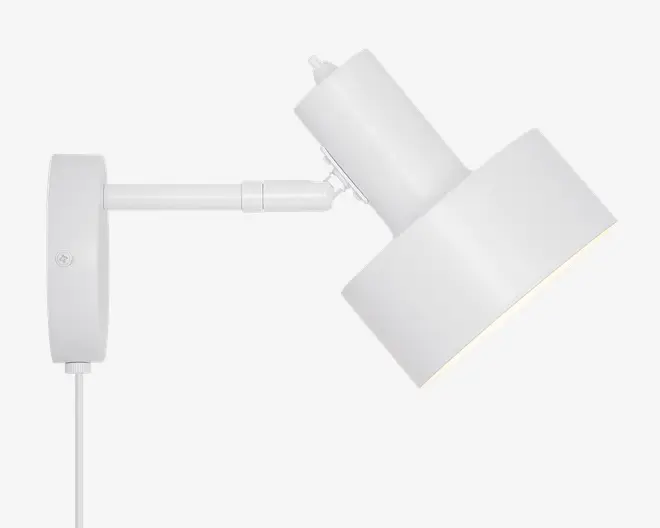 Moderne vægmonteret lampe med mat hvid finish, cylindrisk justerbar arm og bred, vinklet lampeskærm. Lampen har en synlig ledning og et enkelt, minimalistisk design, der passer til moderne indretning.